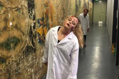 Zombies in lab coats in graffitied hallway