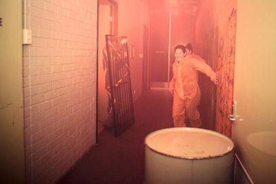 Players running through hallway with zombie behind bars