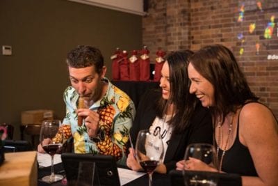 Man smelling a vial while 2 people laugh