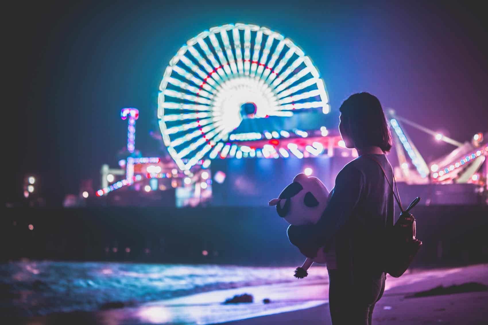 Girl standing on beach with ferris wheel in background