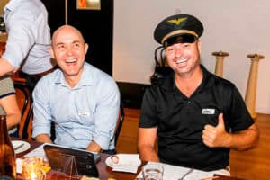 2 men sitting at a table laughing during client appreciation event