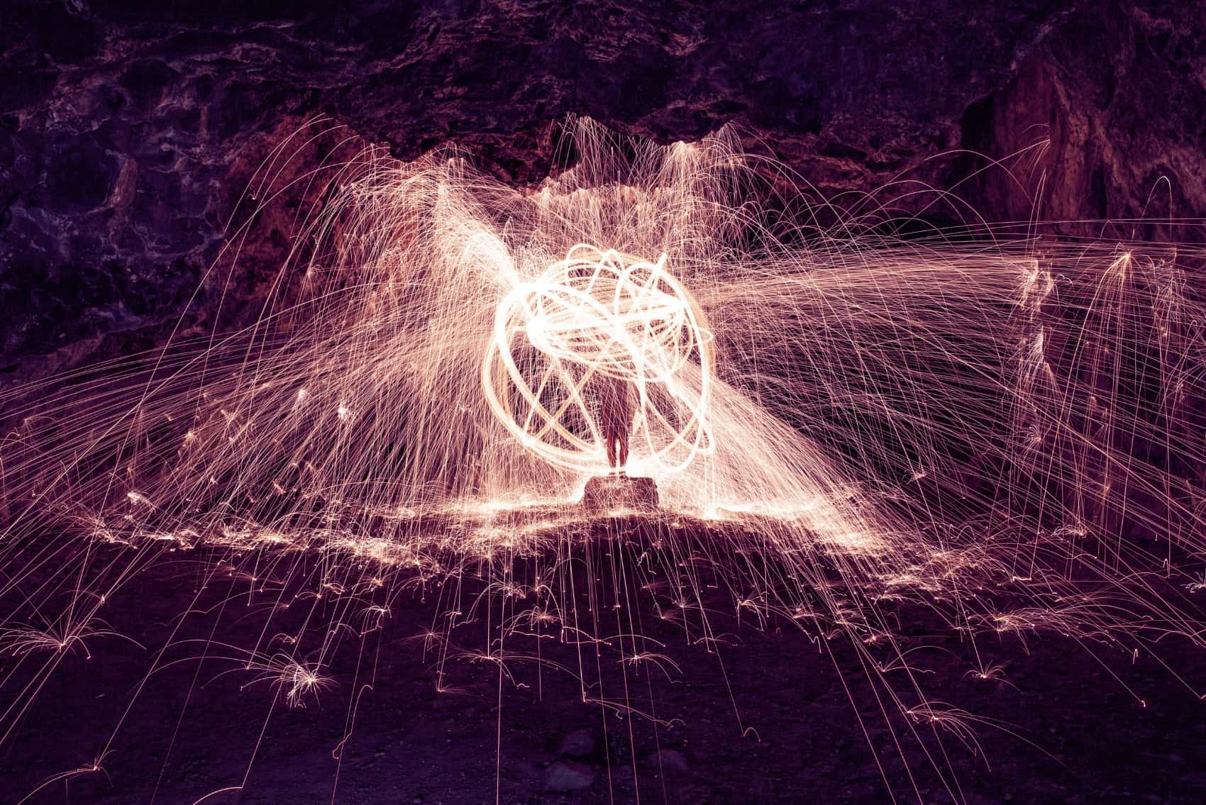 Sparklers glowing purple in a cave