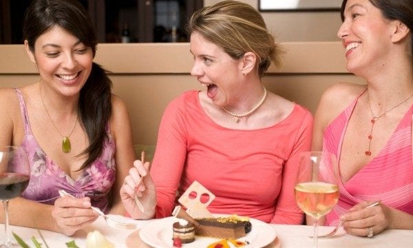 3 women laughing while eating desert