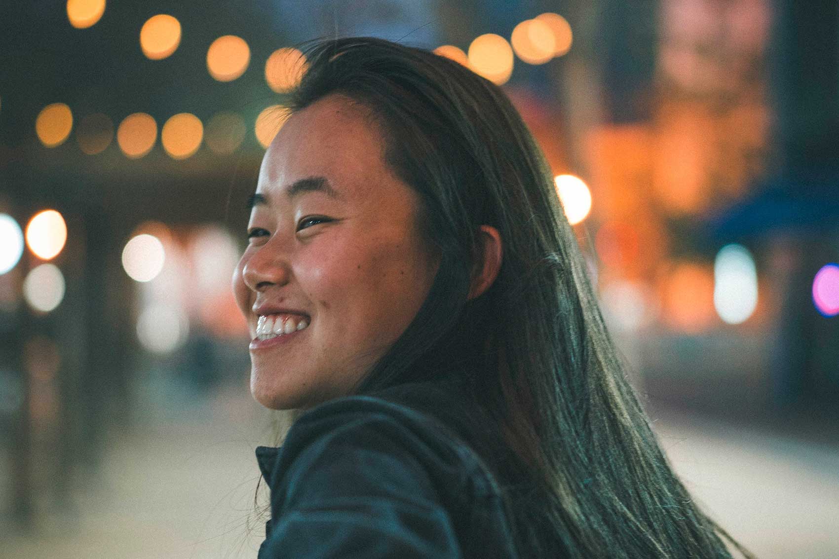 Portrait of happy asian woman with blurred lights in background