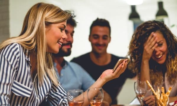 Group of people laughing and looking at a smart phone